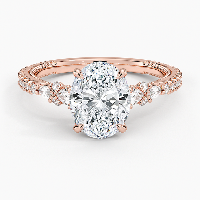 Oval moissanite with pear and round accent clusters on a milgrain pave rose gold band, top view