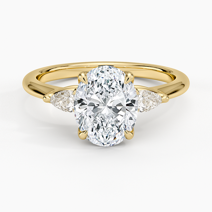 Oval moissanite with pear cut side stones in yellow gold, top view