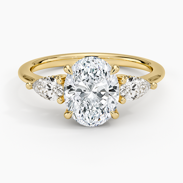 Oval moissanite with pear side stones on a fine yellow gold band, top view