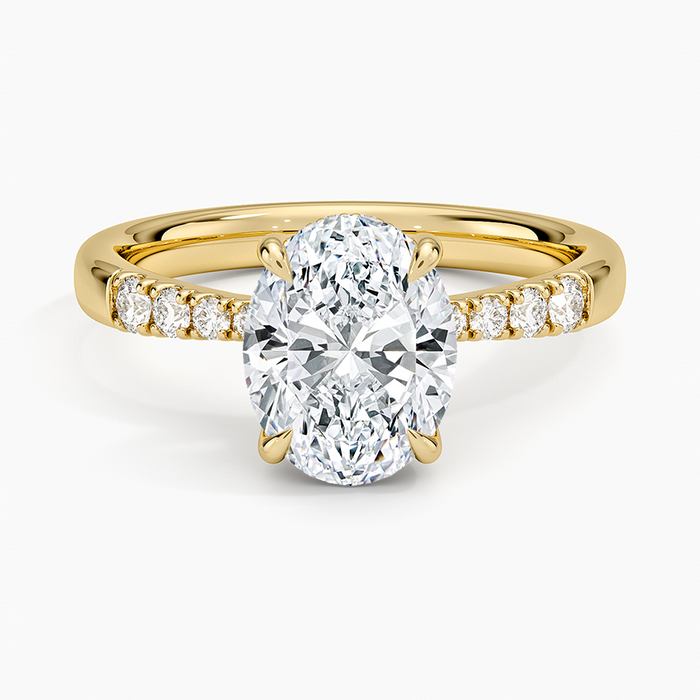 Oval moissanite with small pave accents on a rounded yellow gold band, top view