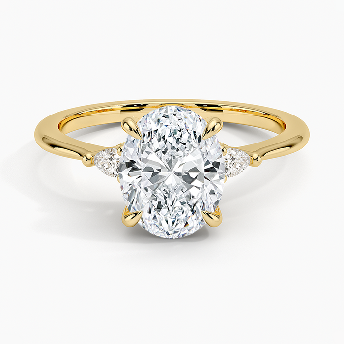 Oval moissanite ring with petite pear side stones in yellow gold, top view
