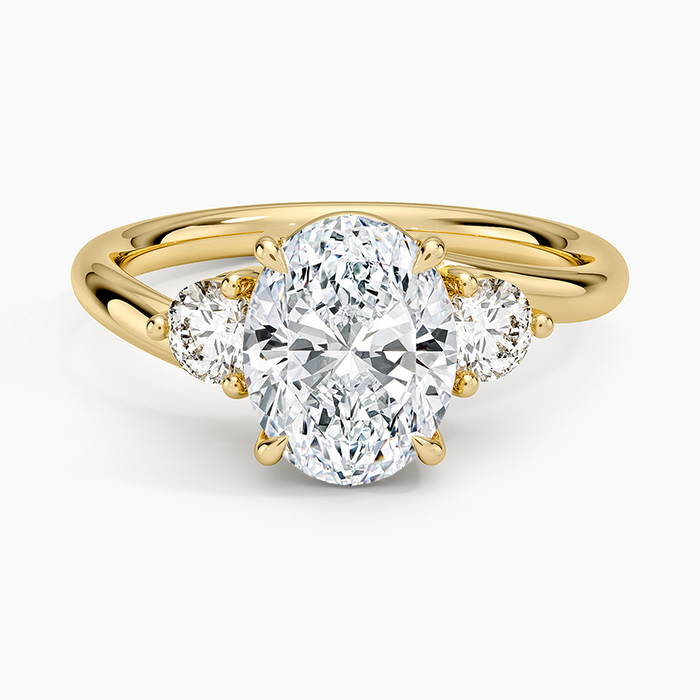Oval moissanite three stone ring with round side stones in yellow gold, top view
