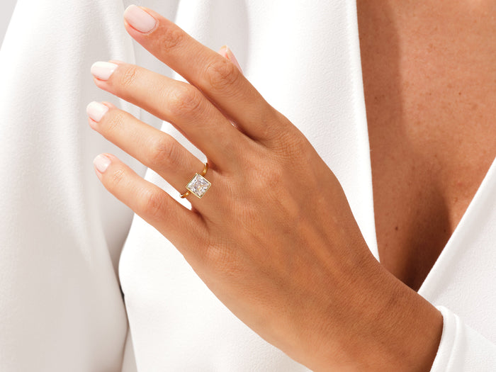 Princess lab grown diamond rub over bezel ring in yellow gold worn on a relaxed hand