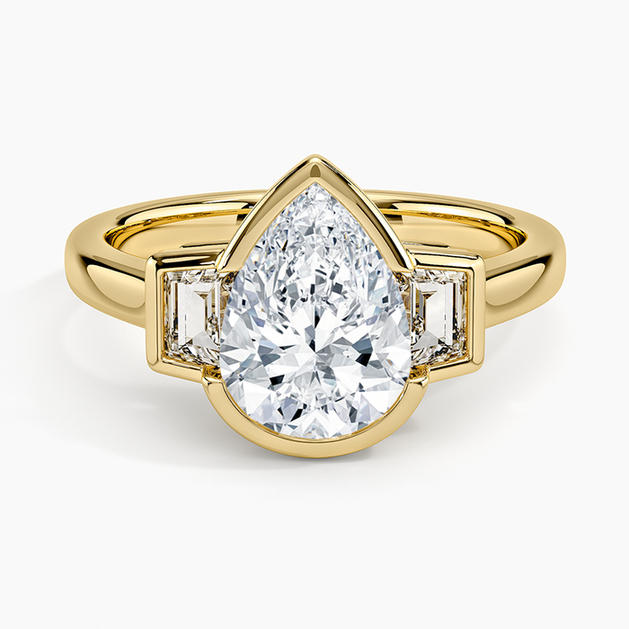 Bezel set pear cut moissanite flanked by tapered baguettes in yellow gold, top view