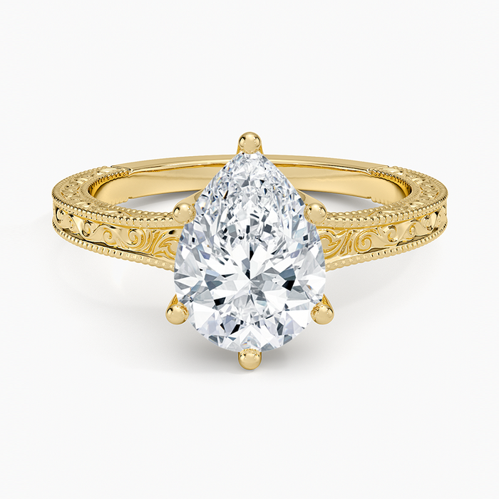 Pear cut moissanite on a flat faced band engraved with a scroll and milgrain edges in yellow gold, top view