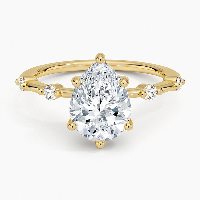 Pear cut moissanite spaced accent constellation engagement ring in yellow gold, top view