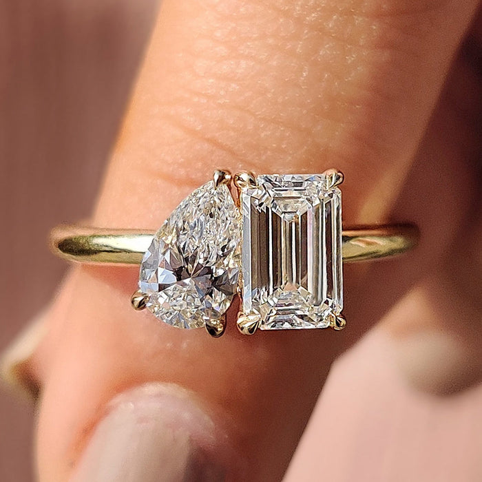 Pear laid east west beside an upright emerald cut moissanite in a toi et moi ring, view 2