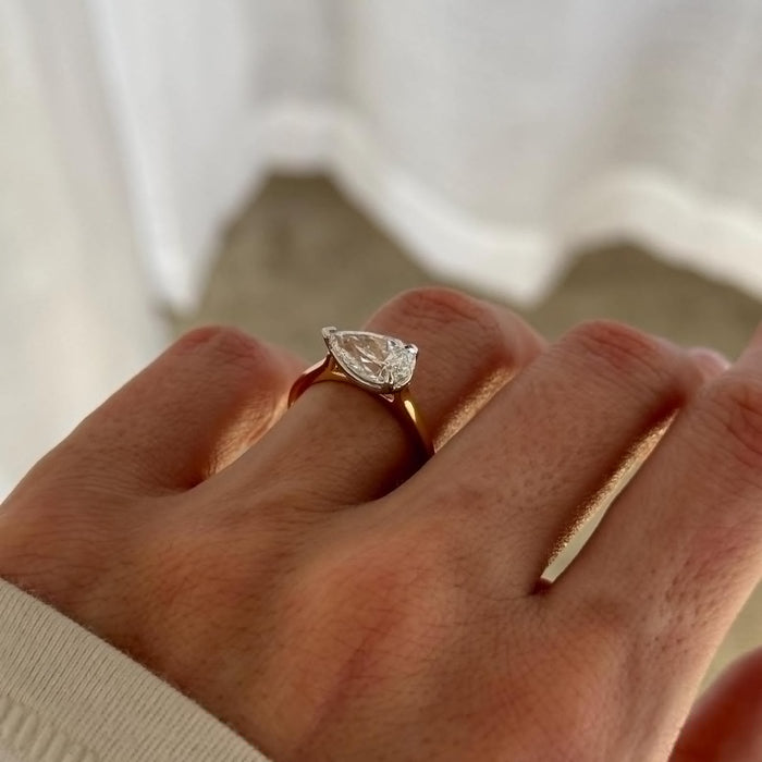 East west pear moissanite solitaire engagement ring on a fine band in yellow gold, view 2