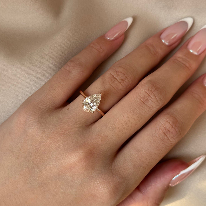 Pear cut moissanite low set solitaire engagement ring on a flat rose gold band