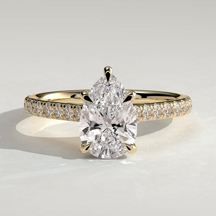 Pear cut moissanite five claw engagement ring on a fine pave yellow gold band