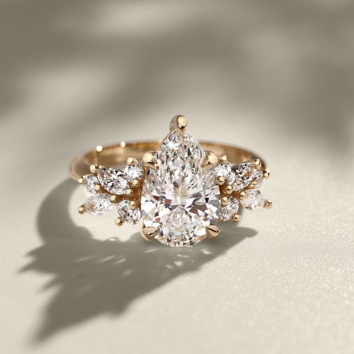 Pear cut moissanite full wing cluster engagement ring in yellow gold