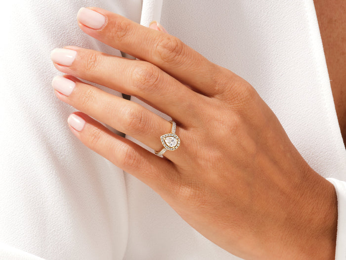 Pear shaped moissanite halo ring in white gold worn on the hand, dainty look