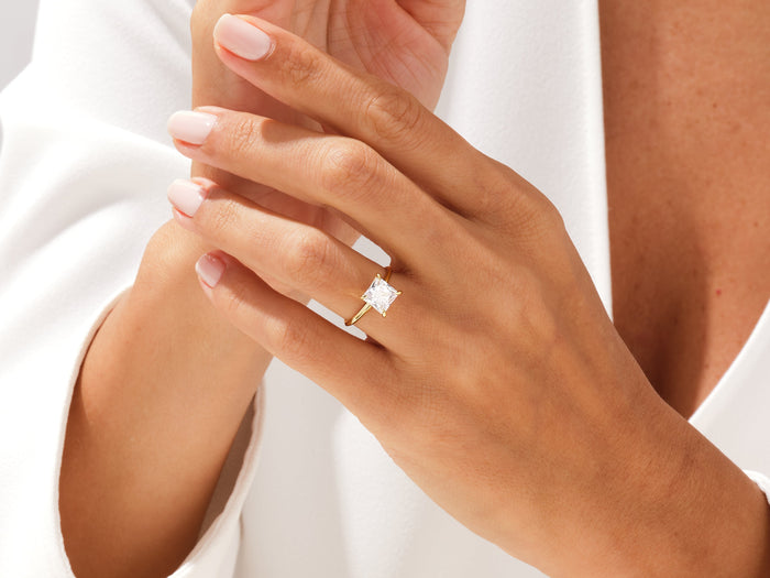 Princess cut lab grown diamond knife edge solitaire on clasped hands against a white shirt