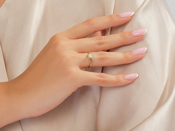 Pear lab grown diamond split shank ring in yellow gold worn on a hand against satin