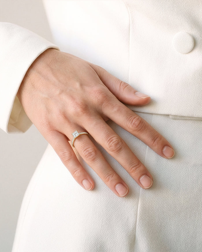 Princess cut lab grown diamond engagement ring worn on the hand against a cream suit
