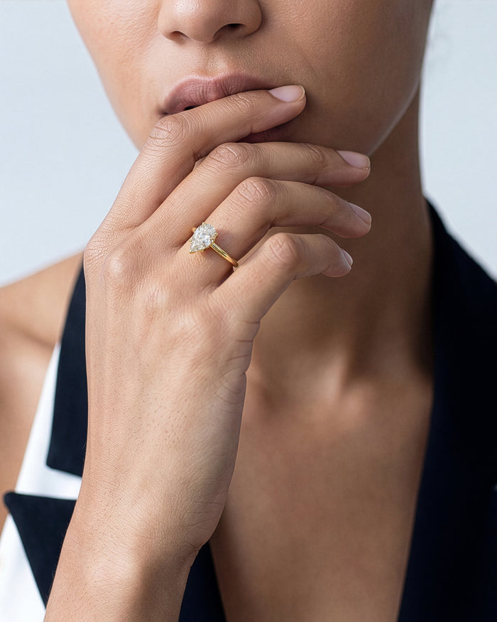 Pear lab grown diamond solitaire in yellow gold worn on the hand at the chin