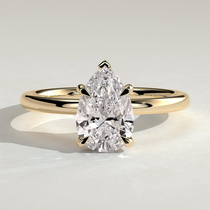 Pear cut moissanite V claw solitaire engagement ring on a domed yellow gold band