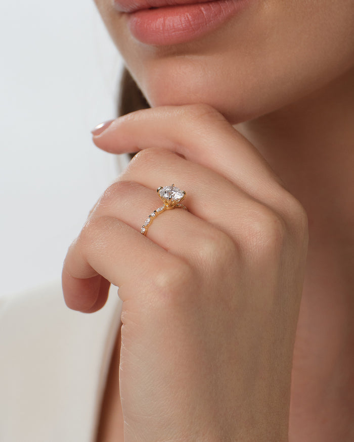 Round lab grown diamond marquise side stone ring in yellow gold worn on the hand under the chin