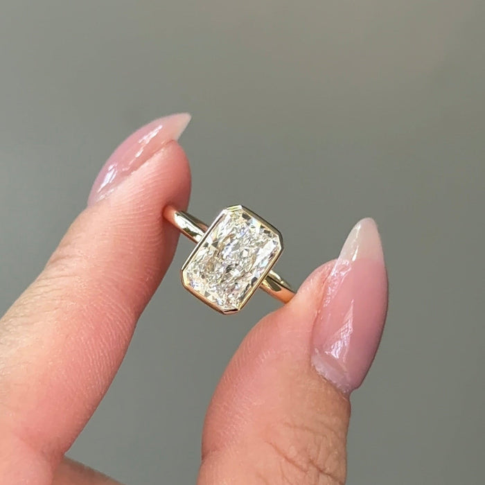 Radiant cut moissanite bezel set solitaire engagement ring in yellow gold