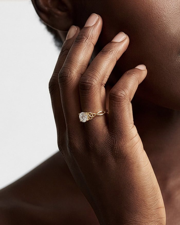 Round lab grown diamond Celtic knot ring in yellow gold worn on the hand at the jaw