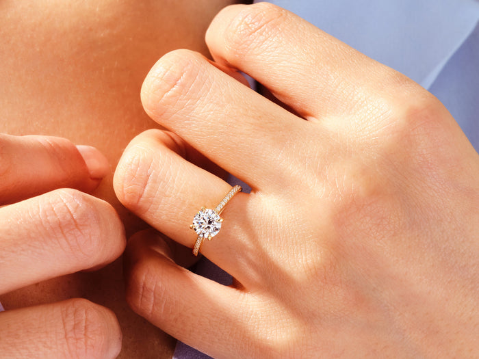 Round lab grown diamond pave cathedral ring in rose gold worn on the hand, fingers at the collar