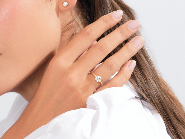 Round moissanite bead and link band engagement ring in yellow gold worn on the hand near the face