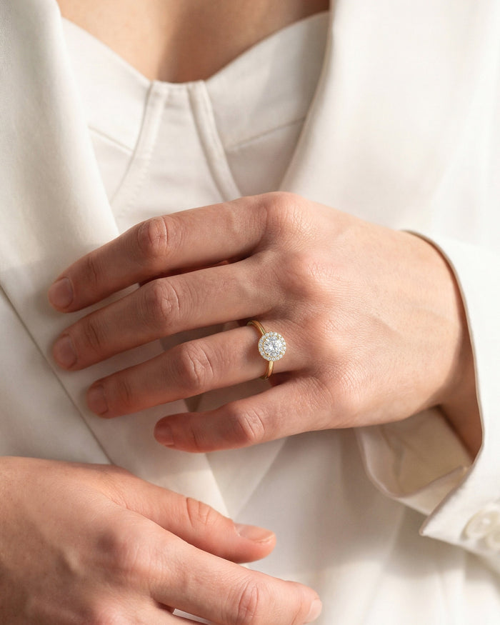 Round moissanite halo engagement ring in yellow gold worn on the hand