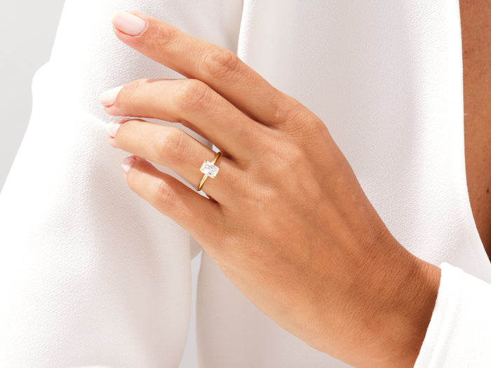 Dainty radiant cut moissanite solitaire in yellow gold worn on the hand
