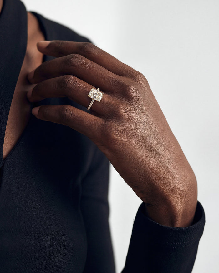 Large radiant moissanite engagement ring in yellow gold worn on the hand