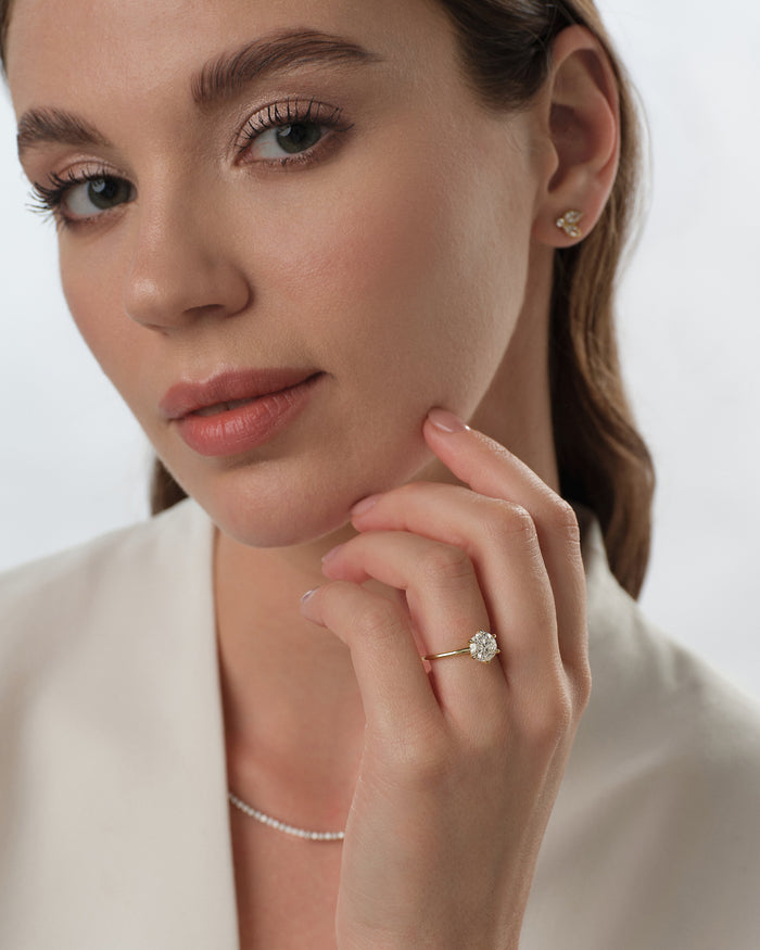 Round lab grown diamond solitaire ring in yellow gold worn on the hand resting at the chin