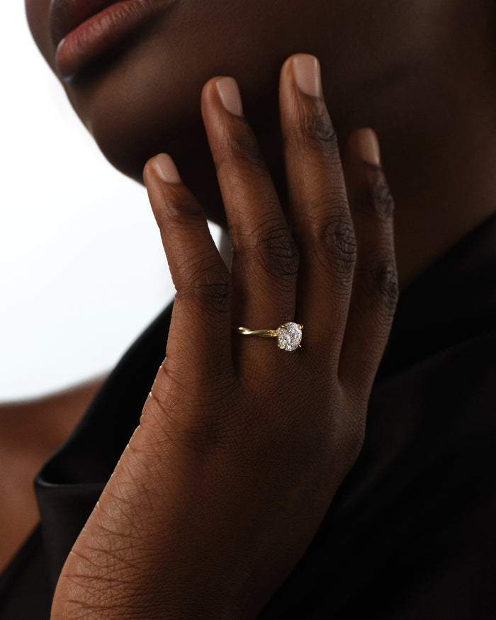 Round moissanite twisted band solitaire ring in yellow gold worn on the hand at the chin