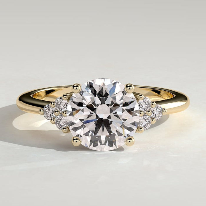 Round brilliant moissanite engagement ring with triangular cluster shoulders in yellow gold