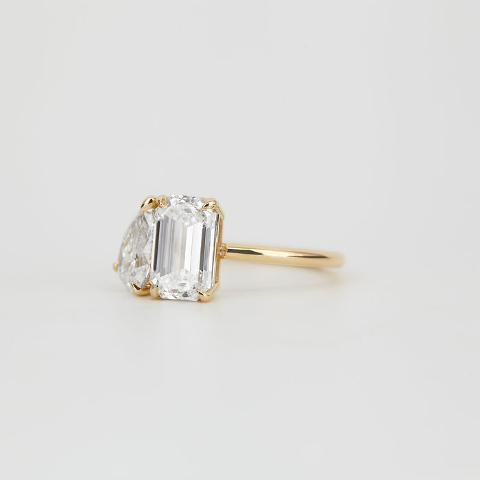 Emerald cut and pear moissanite toi et moi engagement ring on a fine yellow gold band, view 2