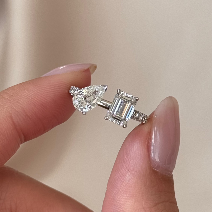 Pear and emerald cut moissanite toi et moi engagement ring with a pave band in white gold
