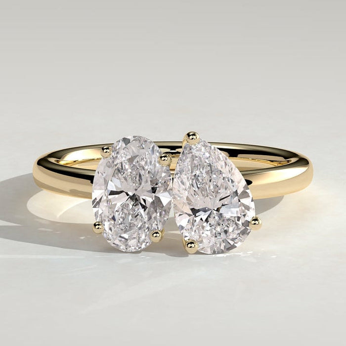 Oval and pear cut moissanite toi et moi engagement ring on a plain yellow gold band