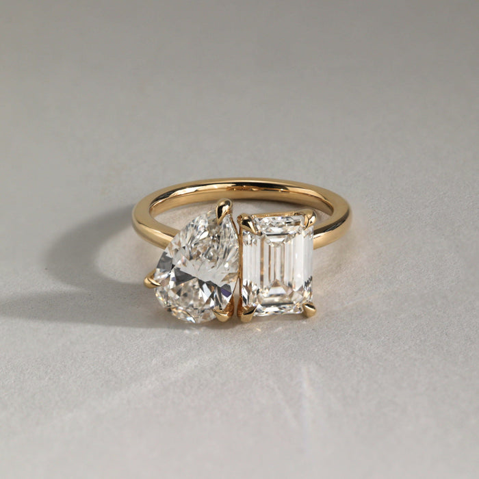 Pear and emerald cut moissanite toi et moi engagement ring on a rounded yellow gold band, view 2