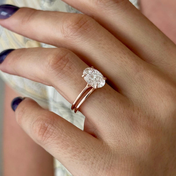 Angled view of four-prong oval lab grown diamond engagement ring with plain rose gold band