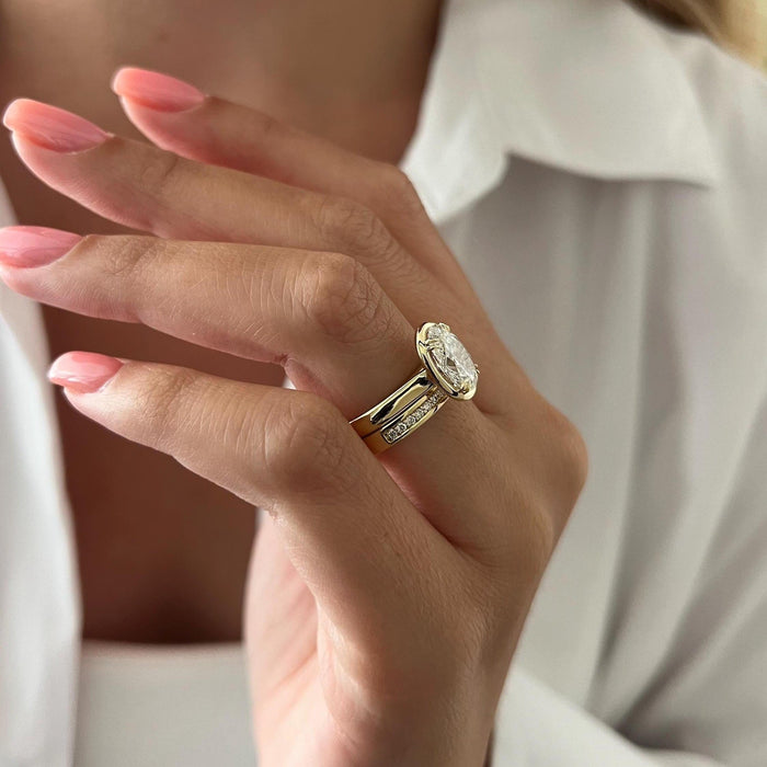 Side view of oval moissanite bezel ring with wide polished shank and straight pave band