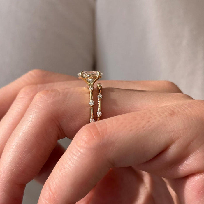 Side view of oval moissanite solitaire and band showing spaced round stones between polished bars