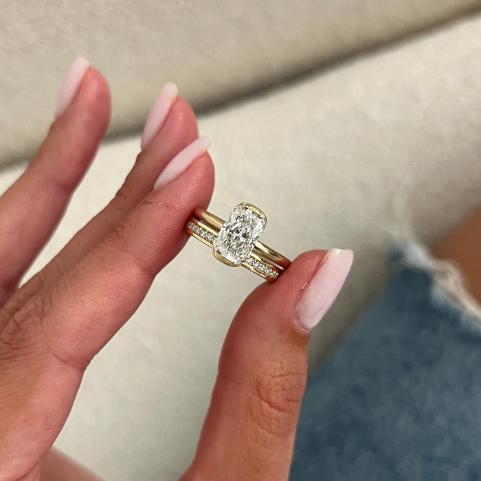 Radiant lab grown diamond half bezel solitaire and straight stone set band held between the fingers