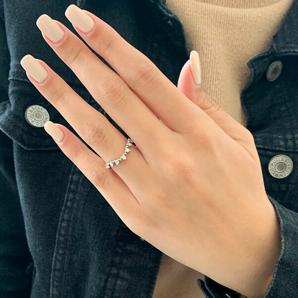 Round moissanite curved wedding band worn on a hand, white gold