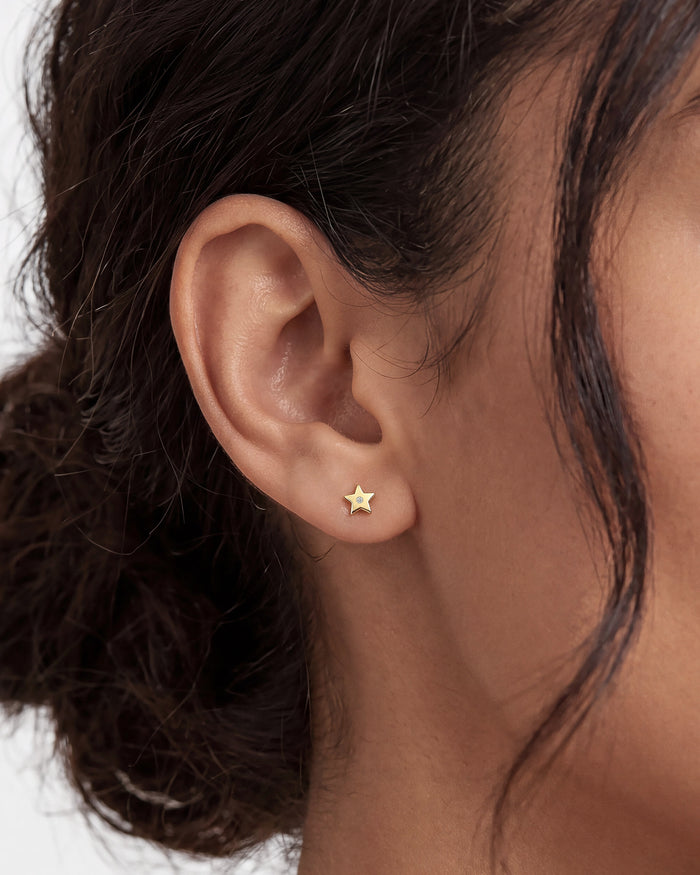 Model wearing round flush set star lab grown diamond stud earrings, close up on the ear