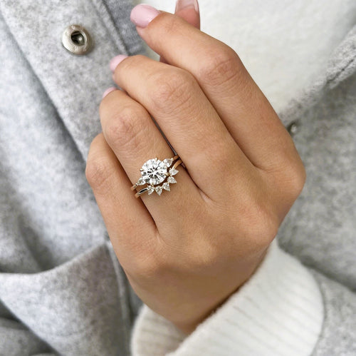 Round moissanite three stone ring with pear crown band in yellow gold on the hand