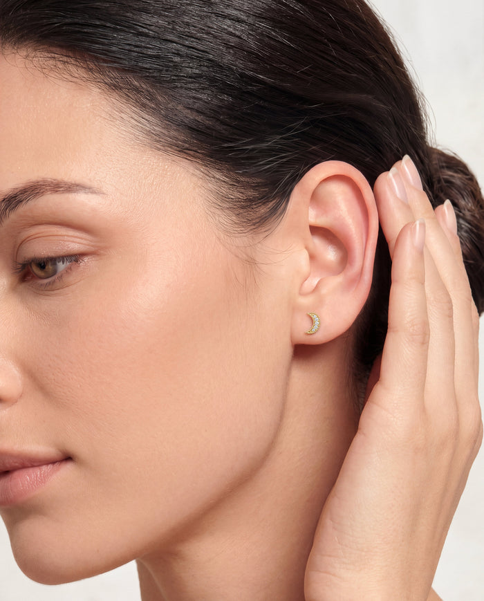 Model wearing round pave crescent moon lab grown diamond stud earrings, close up on the ear