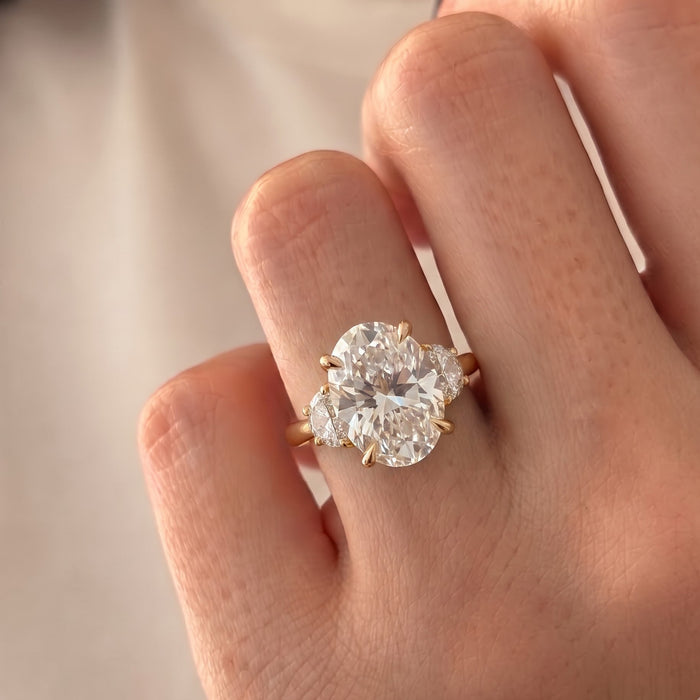 Serena Williams inspired oval moissanite three stone ring with half moon side stones in yellow gold, worn on the hand
