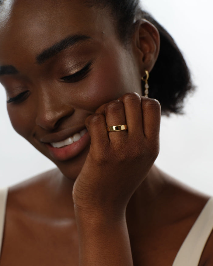 6mm beveled edge gold wedding band worn on a hand