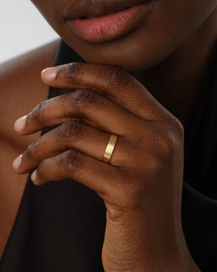 5mm matte brushed gold wedding band worn on a hand