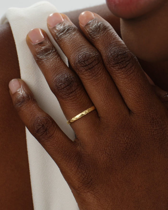 2mm hammered dome gold wedding band worn on the ring finger