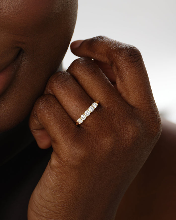 Five stone moissanite anniversary band in yellow gold worn on a hand