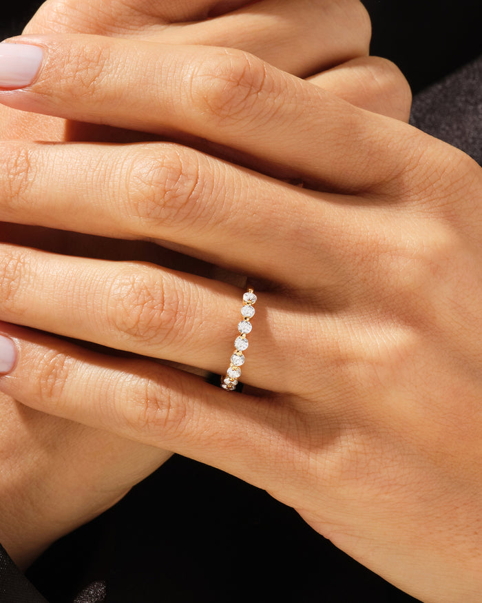 Floating nine stone moissanite band in yellow gold worn on a hand